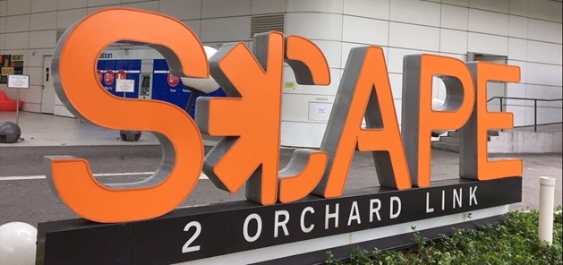 Outdoor commercial 3D letter sign lighting project at SCAPE 2 Orchard Link, illuminated by waterproof injection 3 LED modules, orange large frontlit signage real installation photo.
