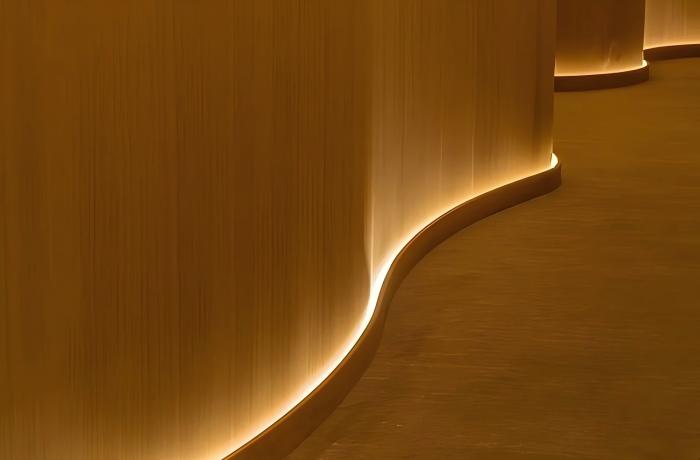 Side‑view SMD LED strip, recessed curved skirting indirect wall ambient lighting for modern interior corridor.